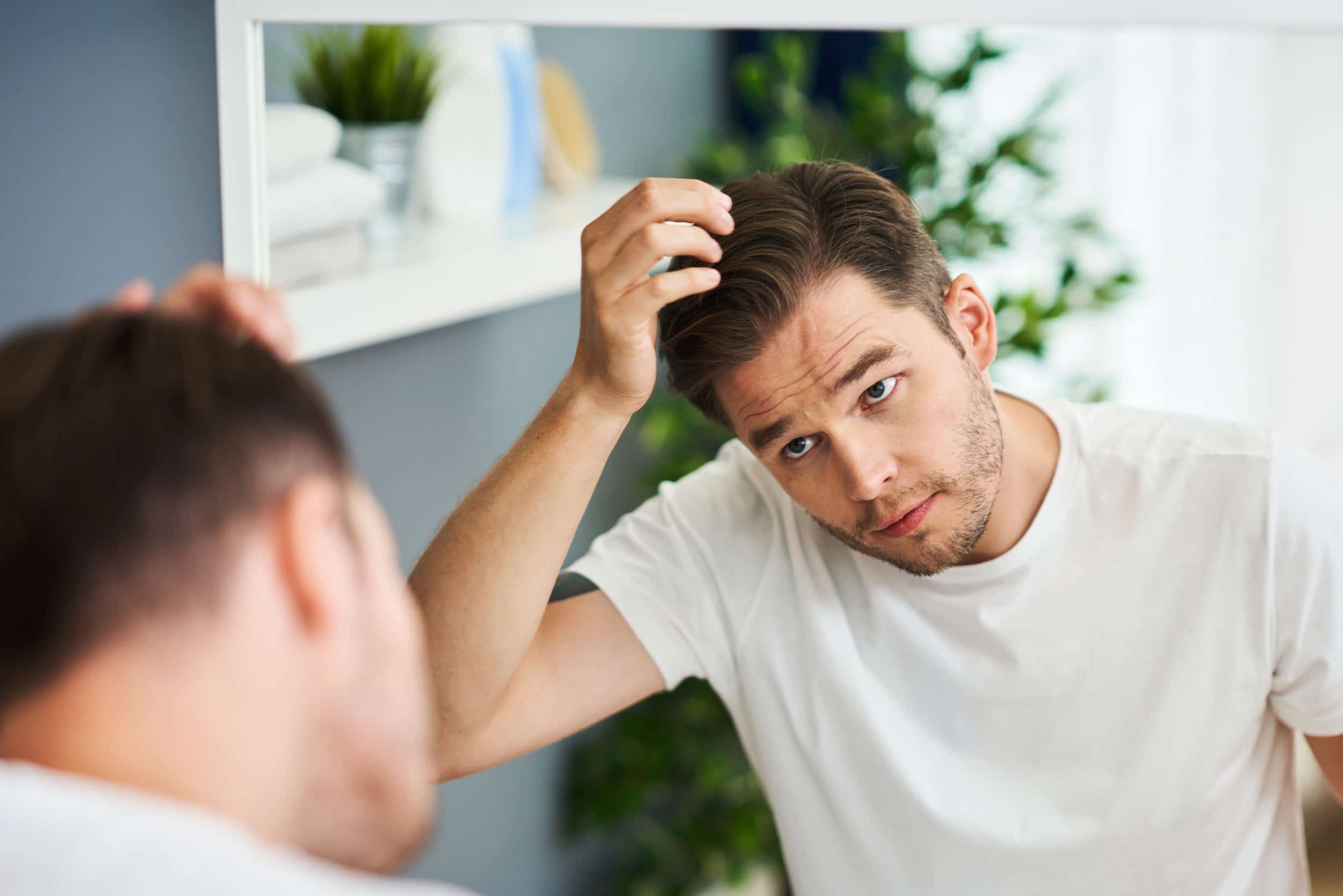 Adult man checking hair condition the bathroom
