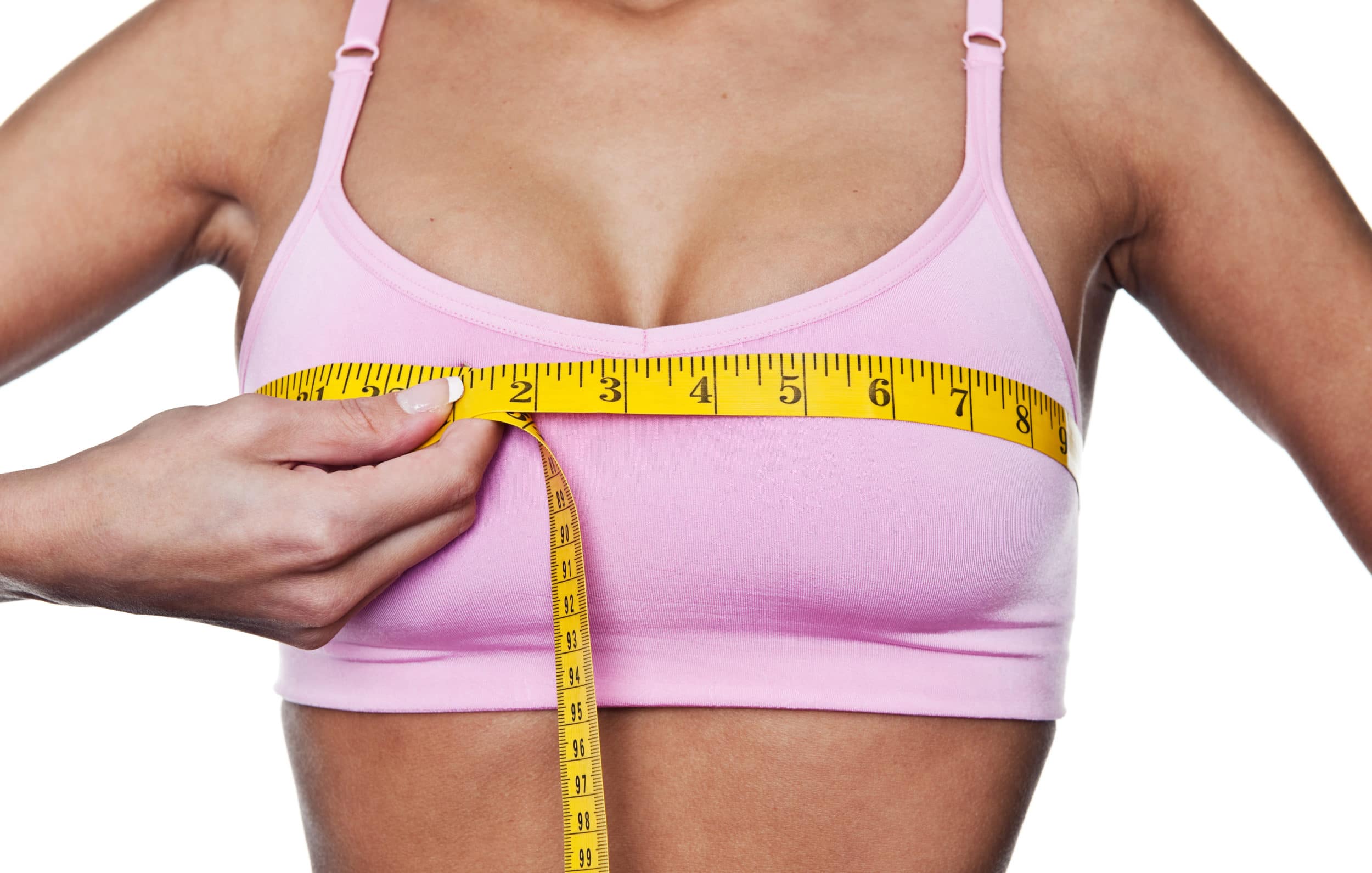 Woman in pink bra measuring her chest with a tape measure