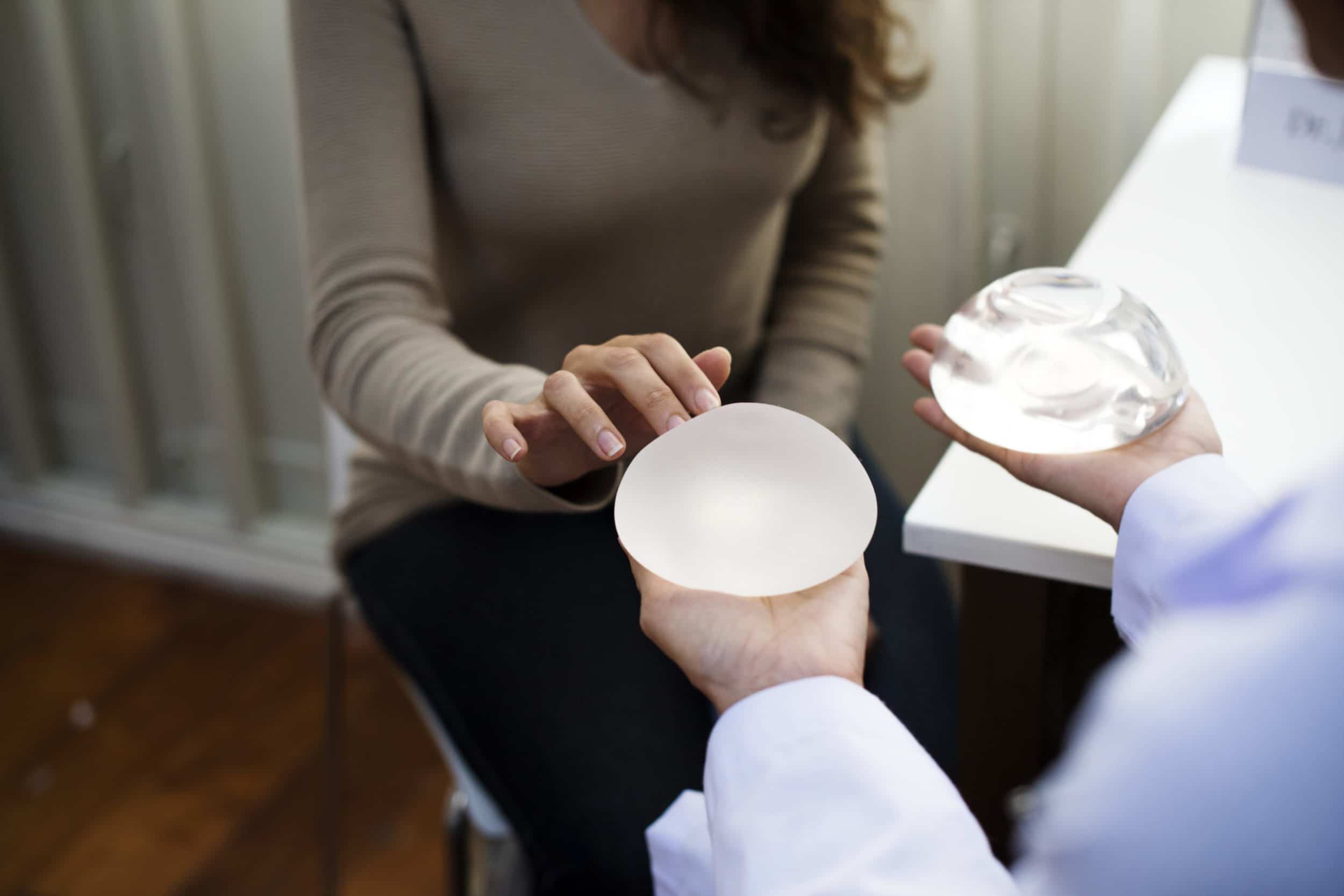 Doctor showing woman different breast implants